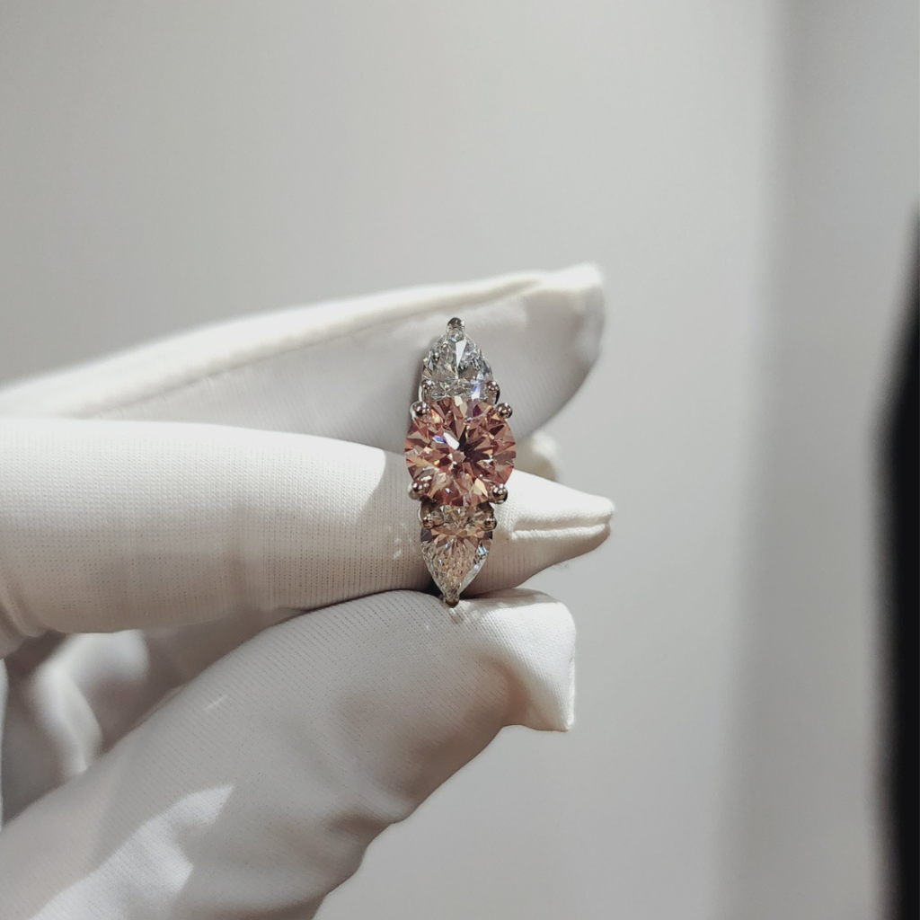 Hand holding pink diamond ring.