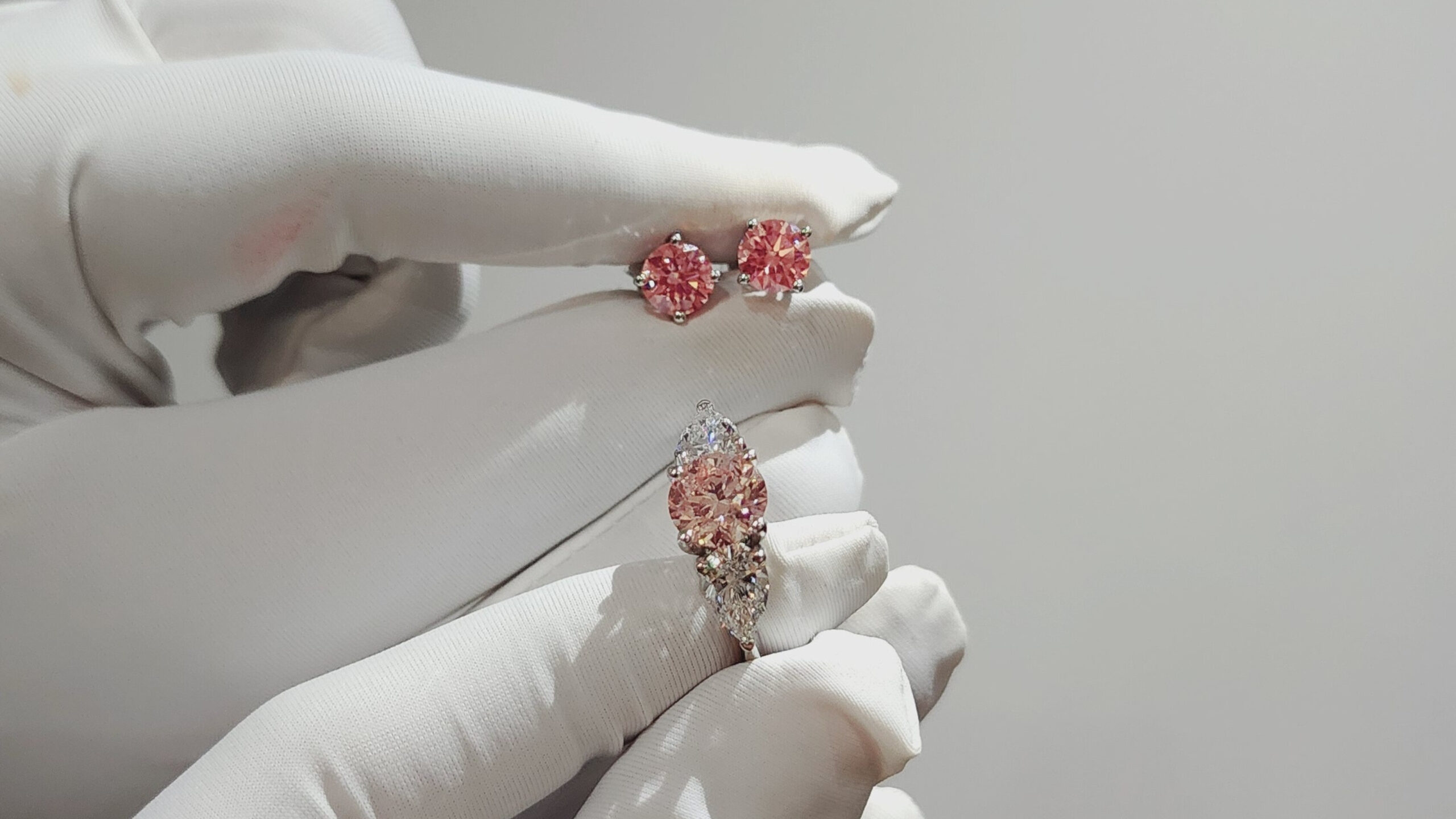 Pink diamond jewelry held with gloves